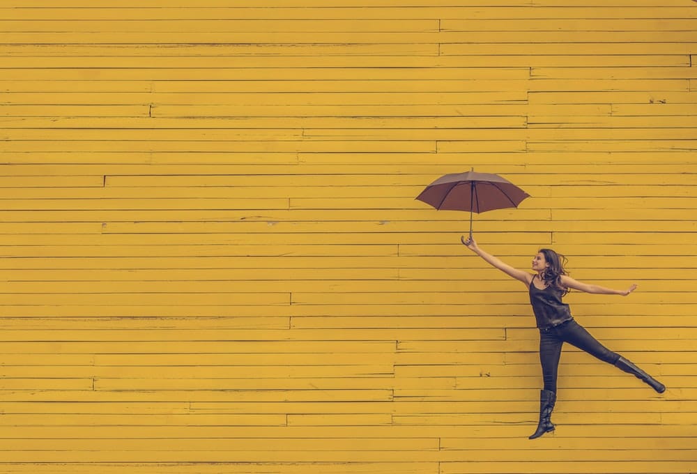 kvinne som holder paraply mens hun hopper